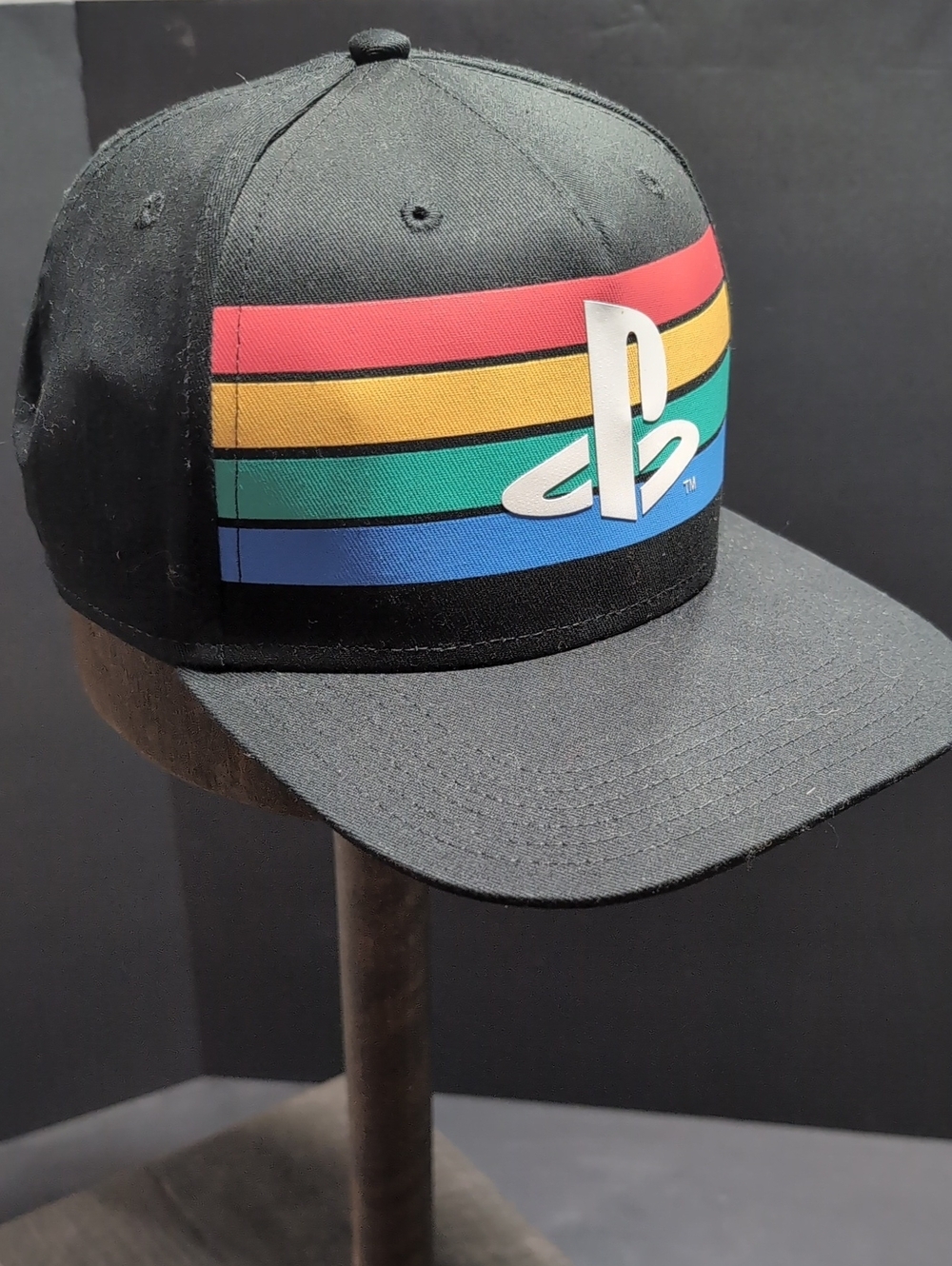 Sony PlayStation Youth Black Snapback Hat with Four Color Rainbow Striped Logo.